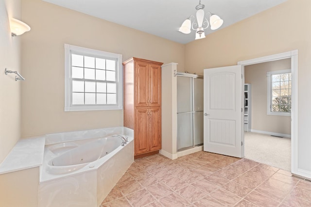 full bathroom featuring a whirlpool tub, a stall shower, baseboards, and a chandelier