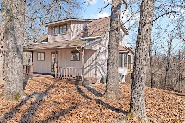 chalet / cabin featuring covered porch and roof with shingles