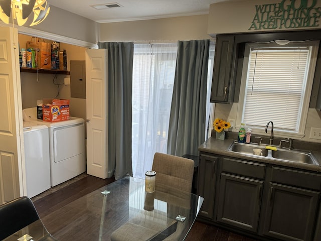 kitchen featuring electric panel, visible vents, dark wood-type flooring, washer and dryer, and a sink