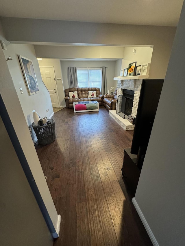 living area with a brick fireplace, wood finished floors, and baseboards