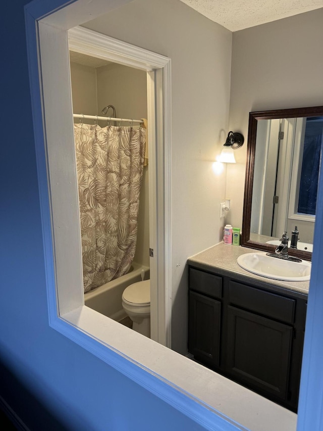 full bathroom featuring shower / tub combo with curtain, a textured ceiling, toilet, and vanity