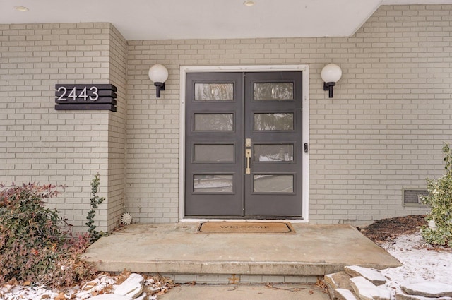 entrance to property featuring crawl space and brick siding