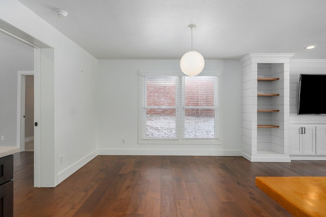 unfurnished dining area with dark wood-style flooring and baseboards