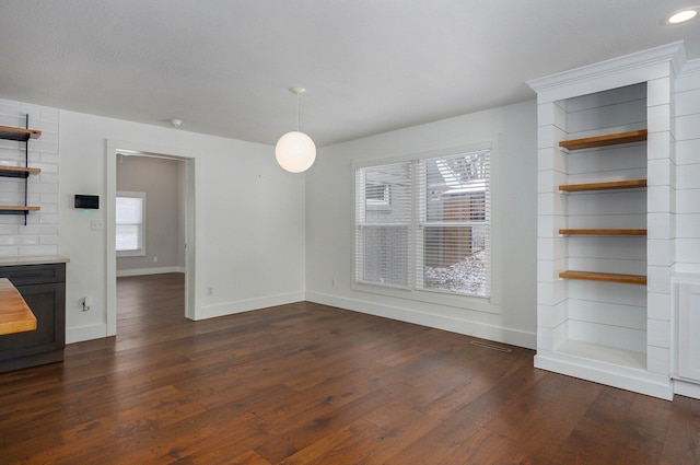 unfurnished dining area with dark wood-style flooring, visible vents, and baseboards