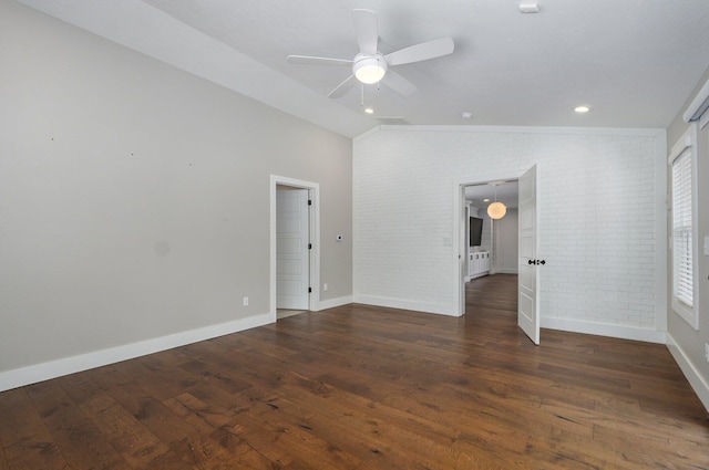 unfurnished bedroom featuring dark wood-style flooring, lofted ceiling, radiator, brick wall, and baseboards