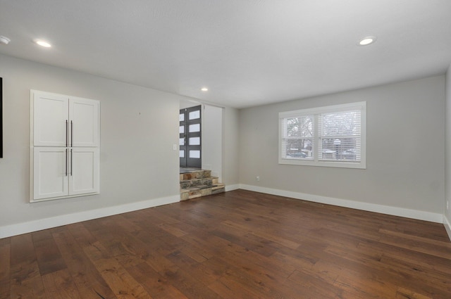 empty room with dark wood-style flooring, recessed lighting, and baseboards