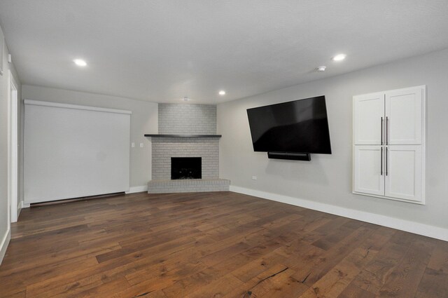 unfurnished living room with a brick fireplace, baseboards, dark wood-style flooring, and recessed lighting