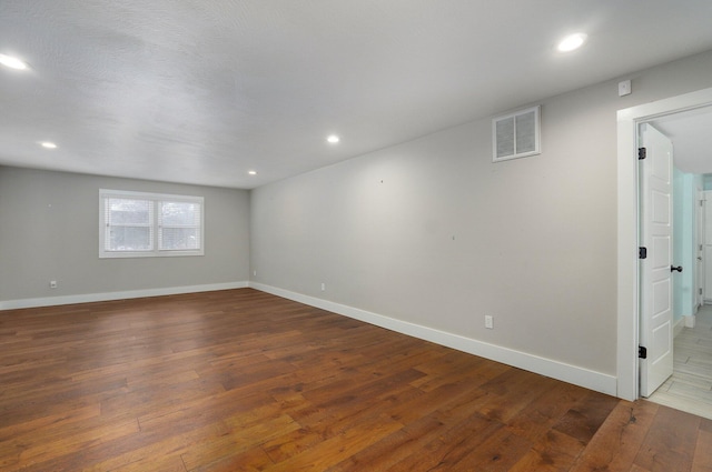 empty room with recessed lighting, visible vents, baseboards, and wood finished floors