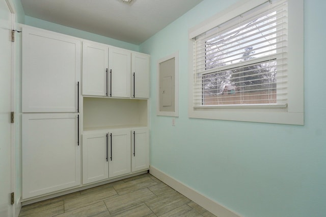 clothes washing area with wood tiled floor, electric panel, and baseboards