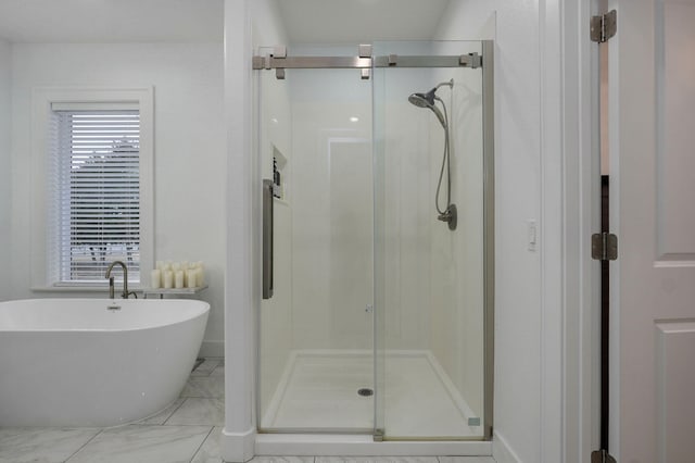 bathroom featuring a wealth of natural light, a stall shower, marble finish floor, and a freestanding bath