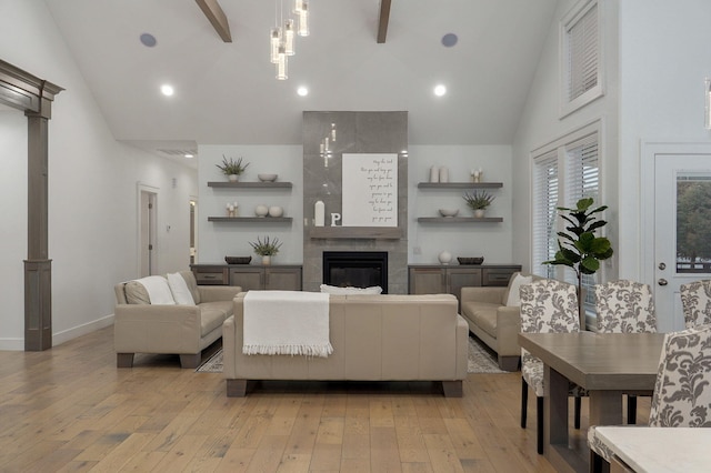 living area featuring light wood-type flooring, high vaulted ceiling, baseboards, and a tile fireplace