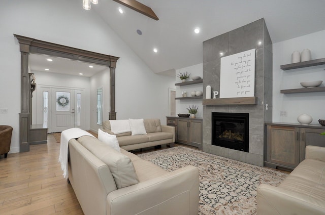 living room with high vaulted ceiling, a tile fireplace, recessed lighting, light wood finished floors, and beamed ceiling