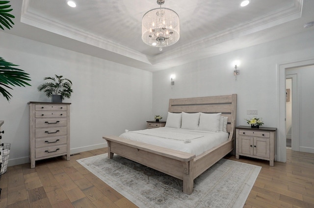 bedroom with ornamental molding, a tray ceiling, light wood-style flooring, and baseboards