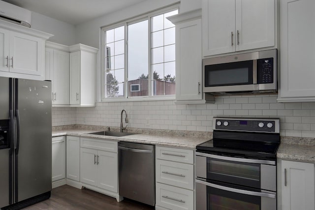 kitchen with backsplash, appliances with stainless steel finishes, white cabinets, and a sink