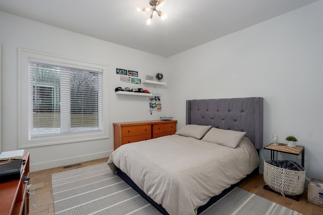 bedroom with baseboards, visible vents, and wood finished floors