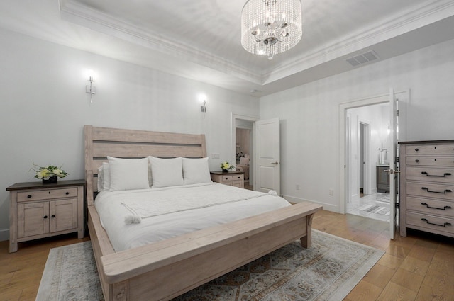 bedroom with visible vents, a raised ceiling, light wood-style flooring, crown molding, and a notable chandelier