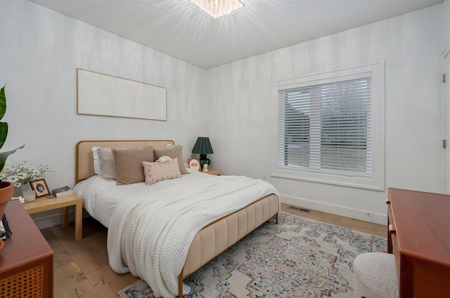 bedroom with light wood-type flooring, visible vents, and baseboards