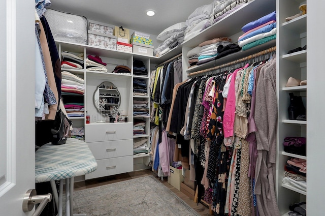 walk in closet with light wood finished floors