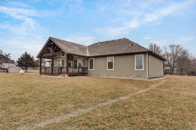 rear view of property with crawl space, a shingled roof, a deck, and a lawn