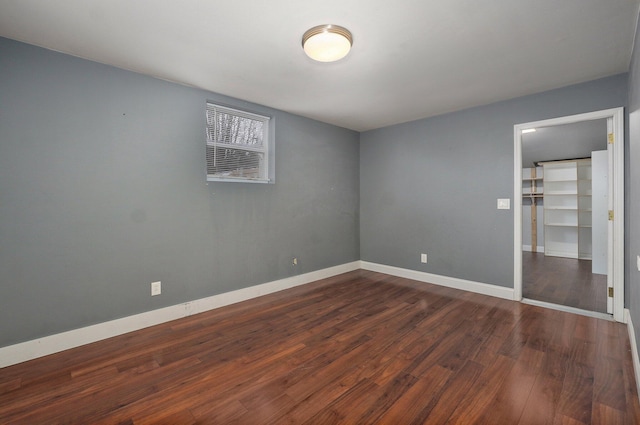 unfurnished bedroom with a closet, baseboards, and dark wood-style flooring