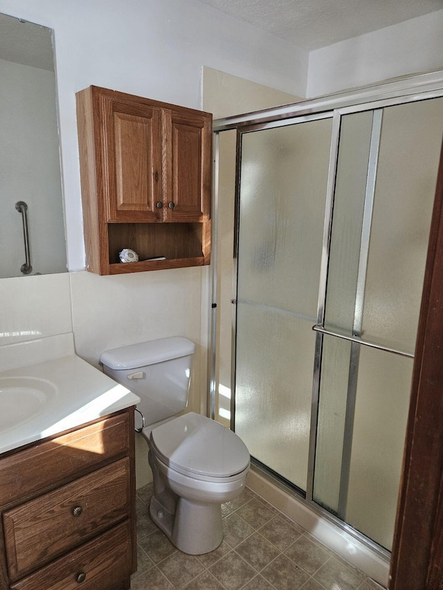 full bathroom featuring toilet, tile patterned floors, a shower stall, and vanity