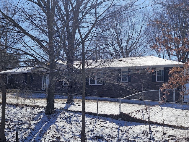 snow covered back of property featuring fence and brick siding