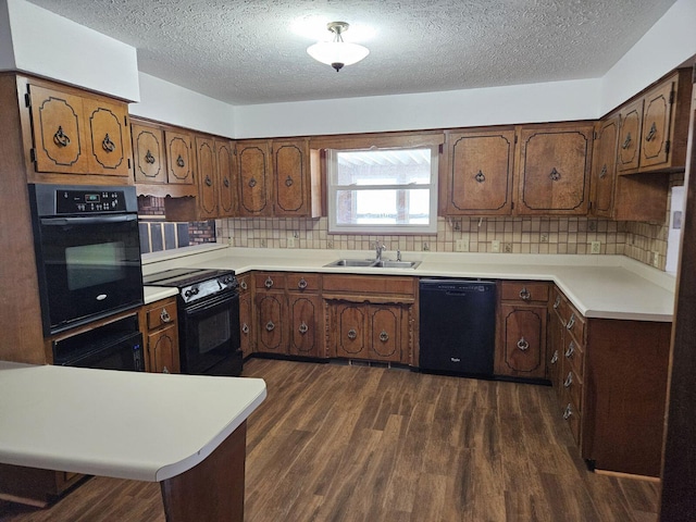 kitchen with black appliances, dark wood-type flooring, light countertops, and a sink