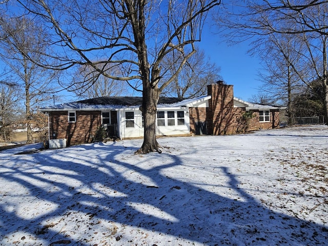 snow covered rear of property featuring a chimney