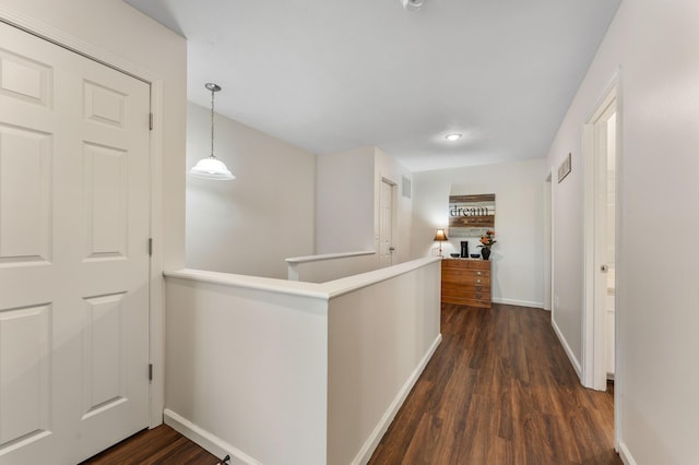 hall with baseboards, visible vents, dark wood-type flooring, and an upstairs landing