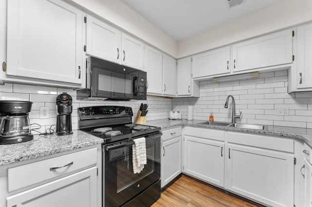 kitchen with black appliances, tasteful backsplash, white cabinets, and a sink