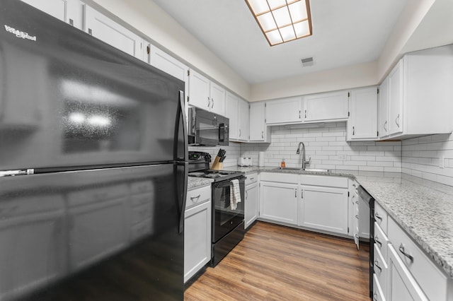 kitchen with black appliances, a sink, visible vents, and white cabinets