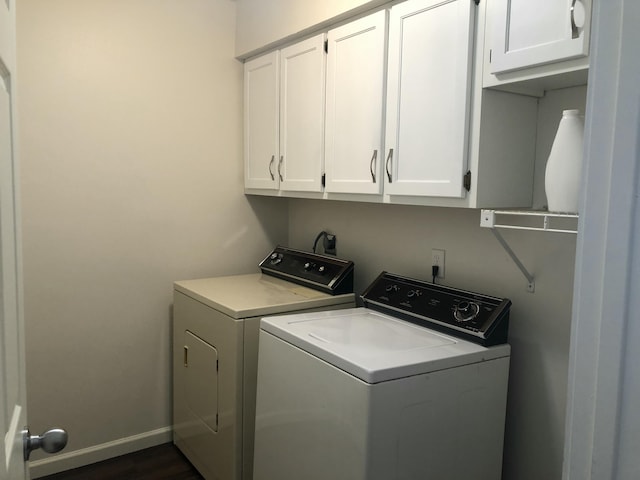 clothes washing area with cabinet space, baseboards, and washer and dryer