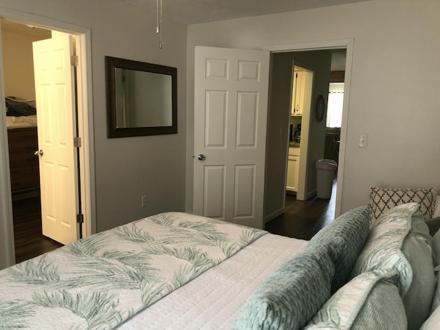 bedroom with a spacious closet and dark wood finished floors