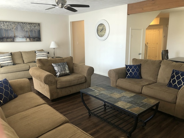 living room featuring dark wood-type flooring, baseboards, and a ceiling fan