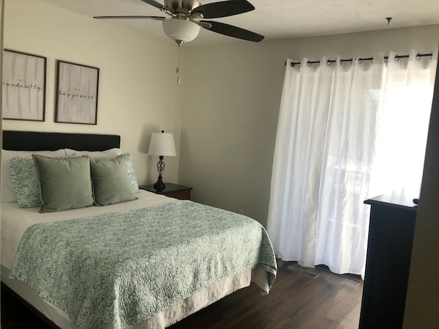 bedroom featuring visible vents, a ceiling fan, and dark wood-style flooring