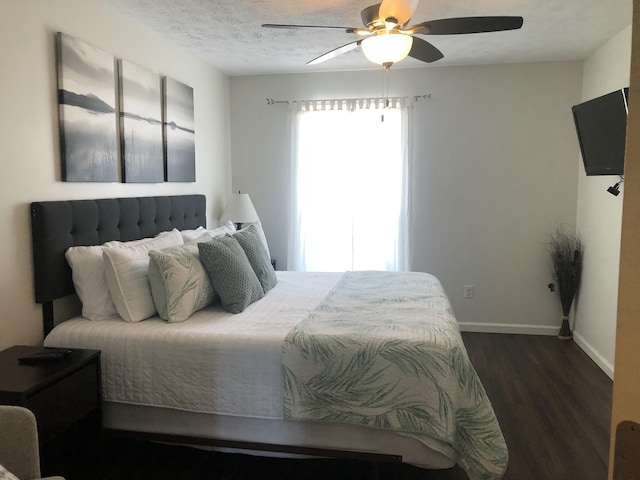 bedroom featuring a textured ceiling, dark wood-type flooring, a ceiling fan, and baseboards