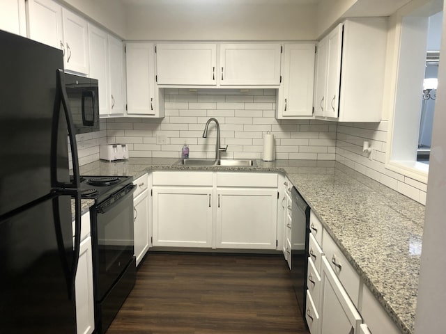 kitchen with light stone countertops, black appliances, white cabinetry, and a sink