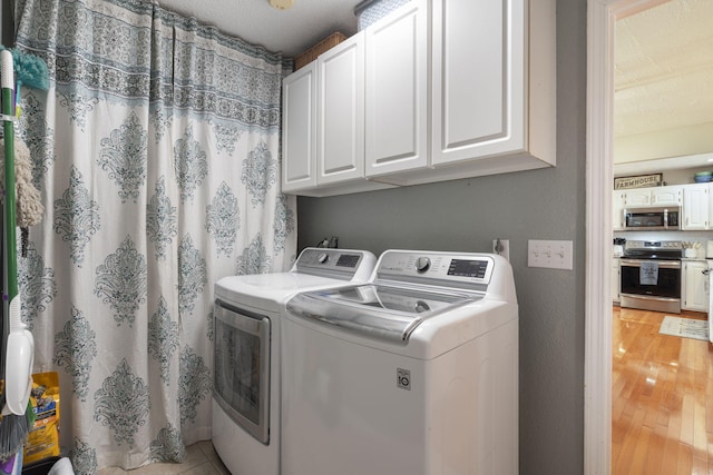 laundry area featuring cabinet space, light wood-style flooring, and separate washer and dryer