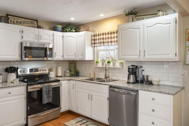 kitchen with white cabinetry, appliances with stainless steel finishes, tasteful backsplash, and a sink