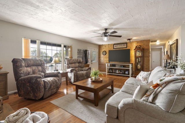 living area with a ceiling fan, visible vents, a textured ceiling, and wood finished floors