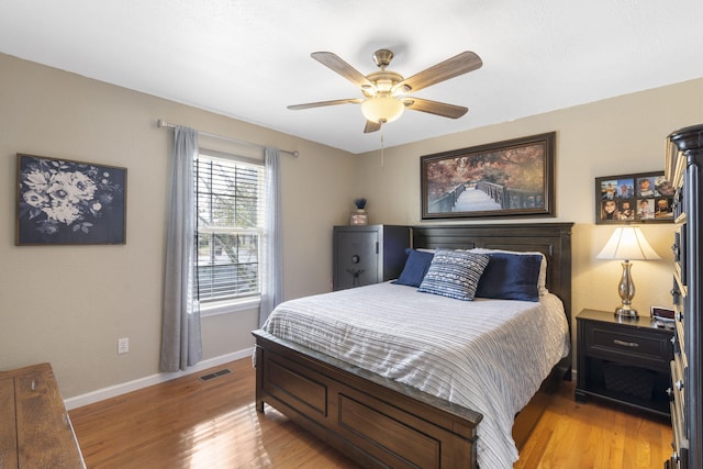 bedroom with baseboards, a ceiling fan, visible vents, and light wood-style floors