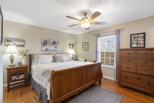 bedroom featuring wood finished floors, a ceiling fan, and baseboards