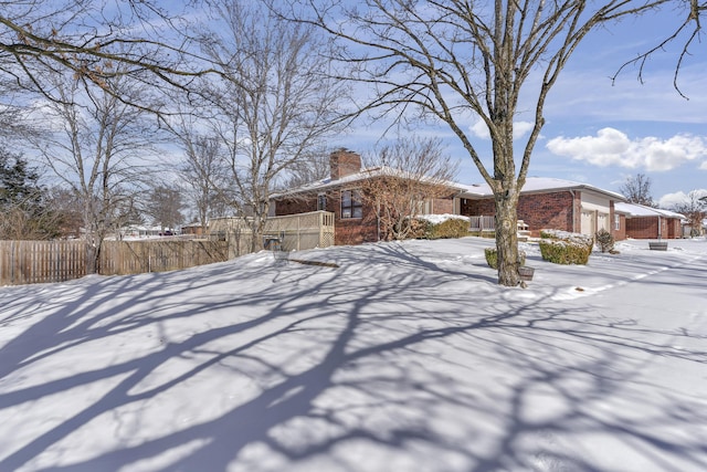 view of front of property featuring brick siding, an attached garage, a chimney, and fence