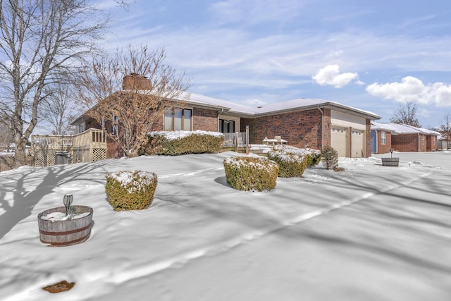 single story home with an attached garage, brick siding, and a chimney