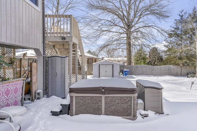 yard layered in snow featuring stairs, a storage shed, an outbuilding, and a fenced backyard