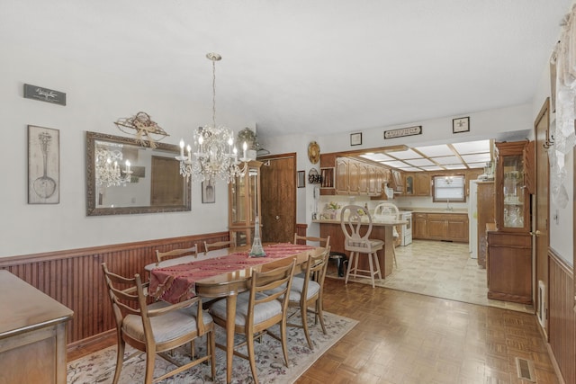 dining space with visible vents, wainscoting, an inviting chandelier, and wooden walls