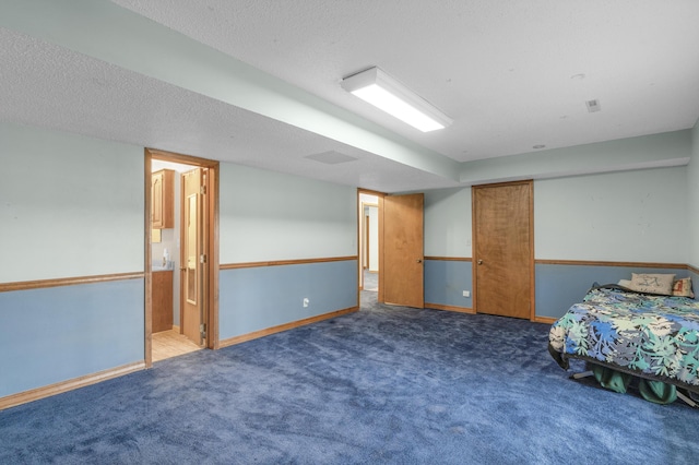 unfurnished bedroom with a textured ceiling, ensuite bath, a closet, carpet floors, and baseboards