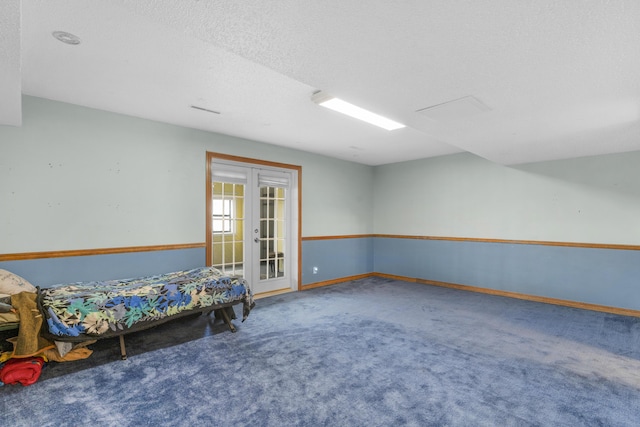 unfurnished bedroom featuring french doors, a textured ceiling, baseboards, and carpet floors