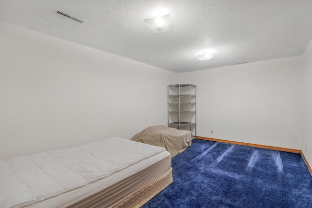 bedroom with baseboards, visible vents, carpet floors, and a textured ceiling