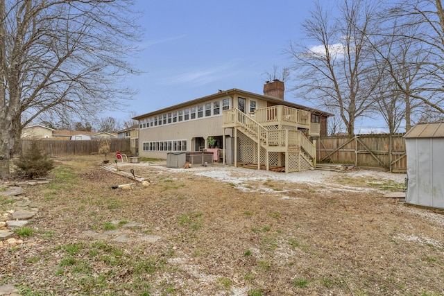 back of house featuring stairway, a chimney, a fenced backyard, a deck, and an outbuilding